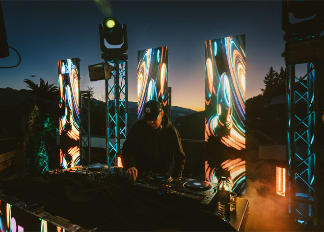 DJ legt bei Sonnenuntergang mit spektakulären LED-Wänden und Lichteffekten auf.