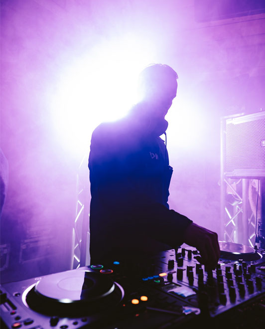 Silhouette eines DJs vor grellem Licht und Nebel, mitten in der Performance.