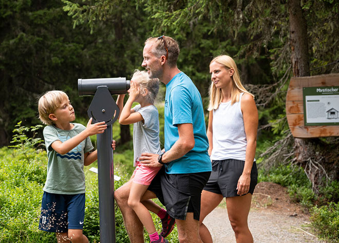 Eine Familie schaut beim Wandern durch ein Fernrohr