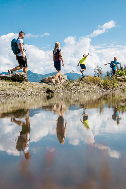 Eine Familie beim Wandern, das Bild spiegelt sich im See