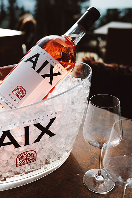 Eine Flasche AIX in einem Weinkühler mit Eis auf der Terrasse.